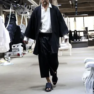 Cardigan nero da uomo con maniche a pipistrello in un ambiente di studio industriale