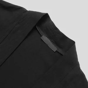 Dettaglio del colletto di un cardigan nero da uomo con maniche a pipistrello, tessuto.