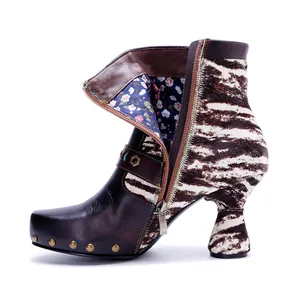 Close-up detail of vintage leather boots with zebra print and metal rivet accents.