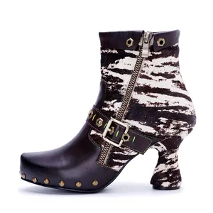Close-up detail of western style leather ankle boot with cow-print fur and studs