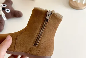 Gros plan d'une botte d'hiver en daim marron pour enfant avec fermeture éclair et fourrure.