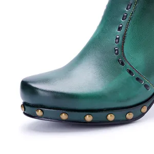 Close-up of green burnished leather boot with rivet detailing and stitching.