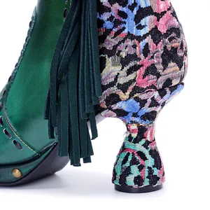 Close-up detail of elegant vintage green leather boot with floral embroidery and tassel fringe