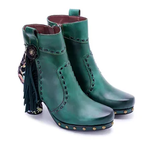 Close-up of green leather boots with fringe and detailed floral print heels