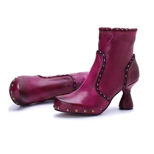 Detailed view of handmade leather ankle boots with distressed finish and metal studs