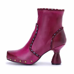 Side view of a handmade magenta leather ankle boot with unique sculpted heel and dots.