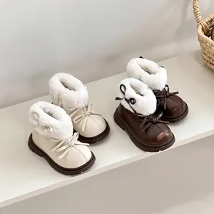 Botas de invierno para niñas con forro de piel sintética y lazos en color crema y marrón.