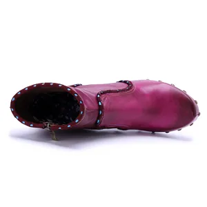 Macro view of handmade magenta leather ankle boot with side zipper and studded sole.