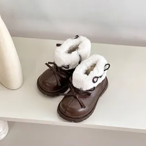 Primer plano de botas de invierno para niños en cuero marrón con forro de pelo blanco.