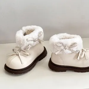 Vista detallada del ribete de piel y lazos en botas de invierno color crema para niñas.