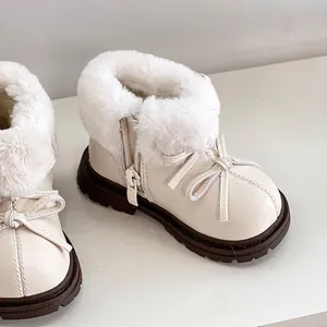 Primer plano de botas de invierno crema para niños con pelo sintético y detalle de lazo