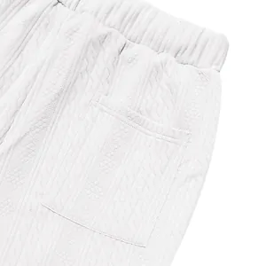 Close-up of white knitted casual pants featuring a textured cable pattern and back pocket.