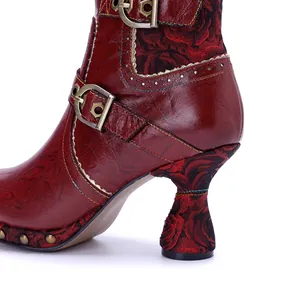 Close-up of vintage handmade leather boots with floral tapestry heel and buckles.