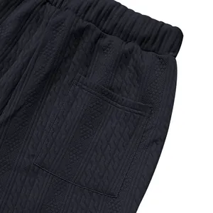Macro detail of men's cable-knit casual pants featuring elastic waist and patch pocket