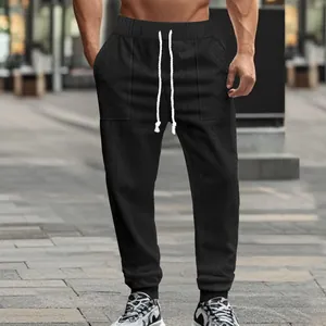 Detail shot of men's black knitted jogger pants with textured fabric and white drawstring.