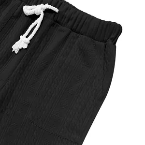 Detail of men's black knit pants featuring white drawstring and textured fabric