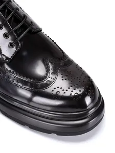Nahaufnahme von schwarzen Brogue-Lederschuhen mit Flügelkappendetails und dicker Sohle