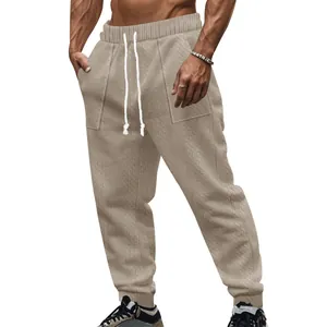 Close-up of men's beige cable-knit joggers with drawstring waist and textured pattern