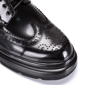 Nahaufnahme von schwarzen Leder-Brogues mit dicker Sohle und Flügelkappen-Verzierung.
