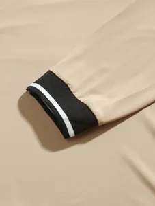 Close-up detail of beige long-sleeve polo shirt showing black ribbed striped cuff