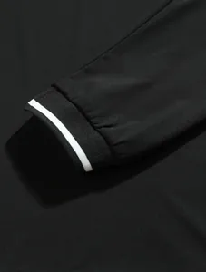 Macro detail view of men's outdoor polo shirt ribbed cuff with white stripe on black fabric.