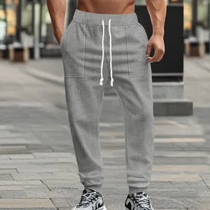 Detail view of men's gray knitted jogger pants featuring drawstring and textured pattern.