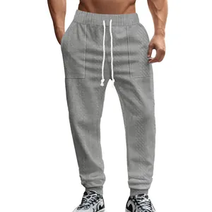 Close-up of men's gray knitted drawstring jogger pants featuring cable knit texture