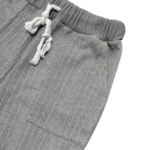 Detail of men's grey knitted trousers showing textured weave and white rope drawstring
