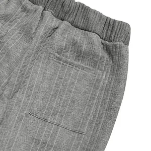 Close-up detail of grey knitted trousers showing premium jacquard texture and pocket.