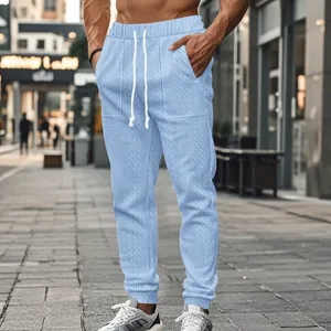 Close-up of men's light blue knitted sports trousers with drawstring and textured pattern.