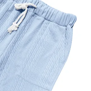 Detail view of light blue men's knit pants featuring textured jacquard and drawstring waist