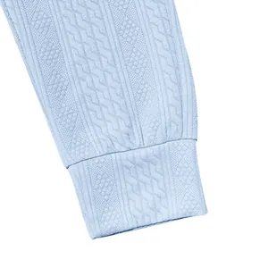 Detailed macro view of light blue men's knitted trousers showing intricate cable knit texture