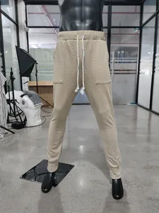 Men's khaki knitted pants displayed on a mannequin showing the texture and fit details