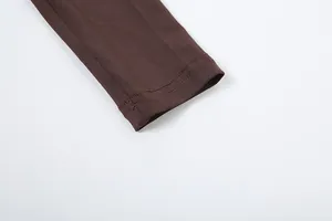 Detailaufnahme der doppelt genähten Manschette eines dunkelbraunen Langarmbodys für Damen