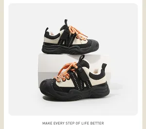 Gros plan sur des baskets d'hiver pour enfants noir et beige avec lacets orange vifs