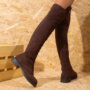 Vue latérale de bottes cuissardes en daim marron avec talons épais et lacets sur le devant.