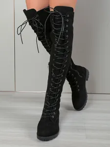 Détail de bottes hautes en daim noir avec lacets à l'avant et talons épais