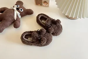 Cozy children's brown fleece loafers featuring soft pom-poms and bows for winter warmth