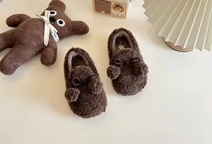 Warm dark brown children's plush loafers featuring cute pom-poms and a bow detail.