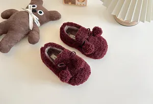Detailed view of burgundy fuzzy kids' slip-on shoes with cute pom-pom and bow accents