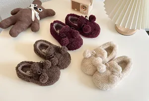 Cozy children's fleece slip-on shoes with pompom and bow details in warm earth tones