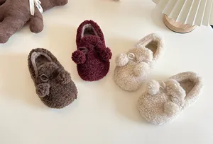 Detailed view showing the soft plush texture of kids fleece slip-on shoes with fuzzy pom-poms