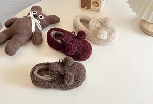 Close-up view of cozy children's fleece slip-on shoes featuring pom-poms and bows