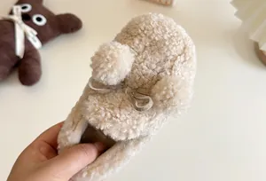 Close-up of fuzzy cream slip-on shoes for girls with cute pom-poms and bow
