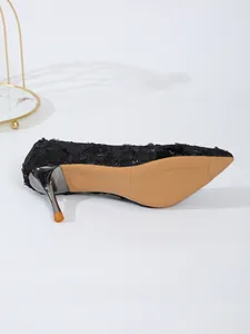 Detailed view of the sole and metallic stiletto heel of a black lace pump shoe