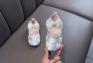 Détail de chaussures de princesse à paillettes argentées pour filles avec strass et nœud en dentelle.