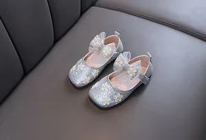Gros plan de chaussures pailletées argentées pour filles avec nœuds en dentelle