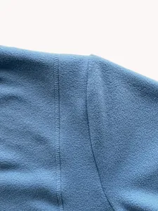 Primo piano della robusta cucitura della spalla di una morbida felpa in pile blu.