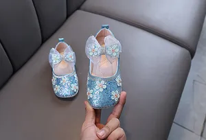 Détail de chaussures de princesse bleues à paillettes pour filles avec fleurs et nœud
