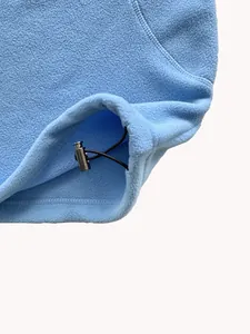 Dettaglio della felpa in pile azzurro con orlo a coulisse regolabile e fermaglio nero